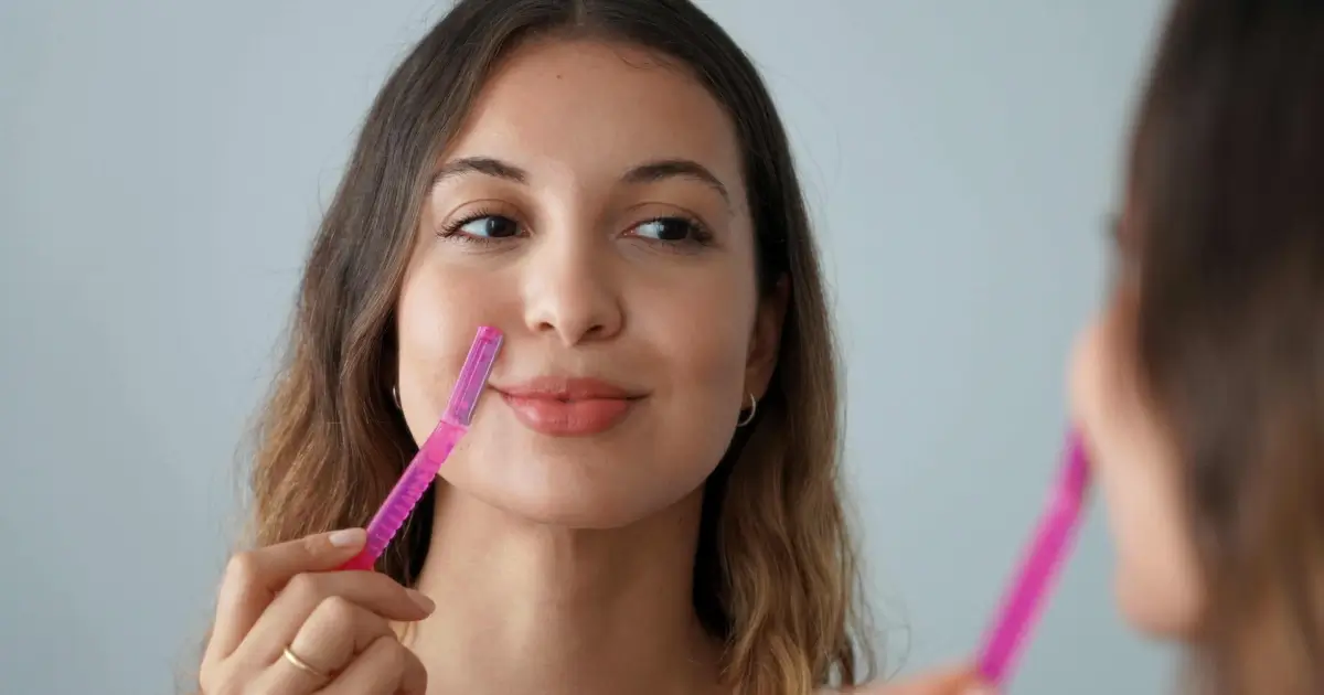 Young woman using a pink dermaplaning tool in Madisonville, LA.