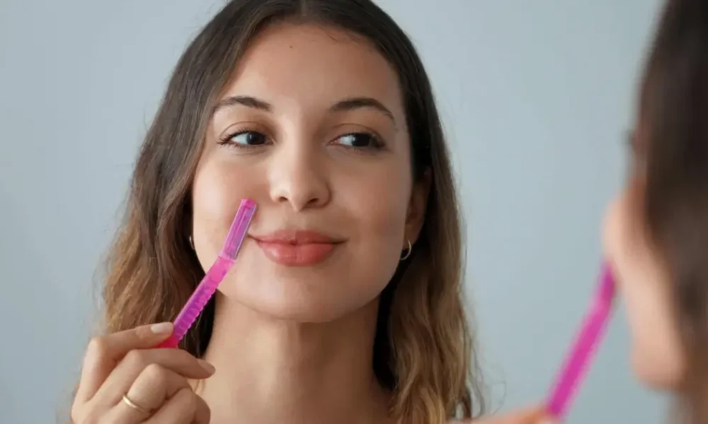 Young woman using a pink dermaplaning tool in Madisonville, LA.